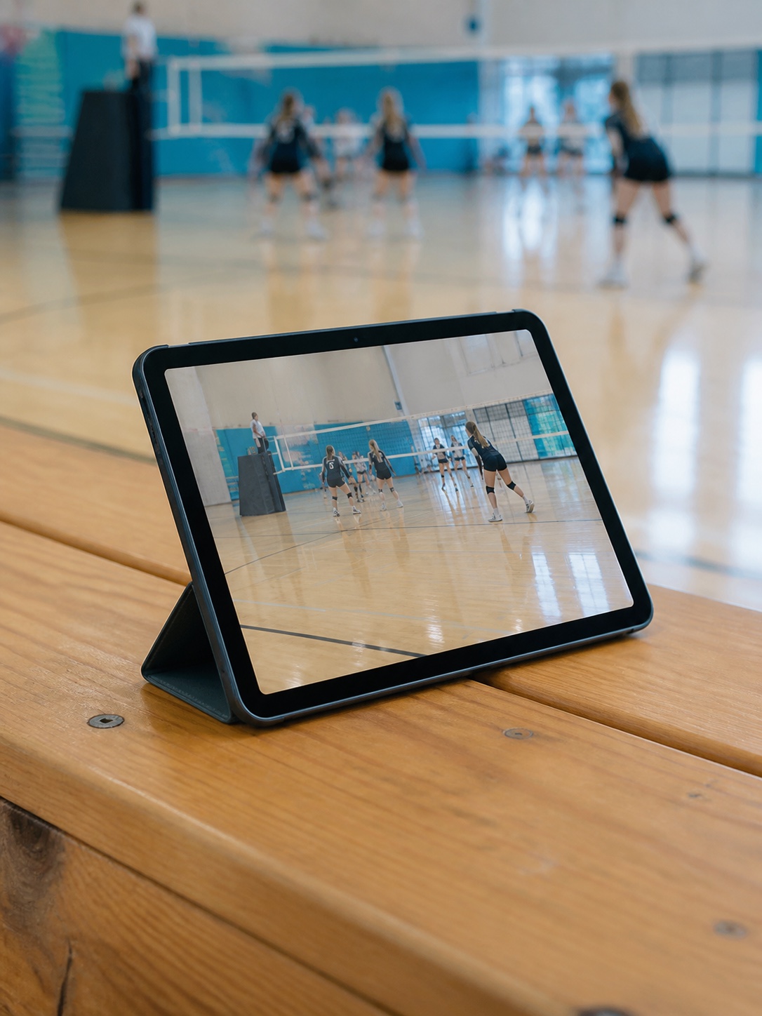 An iPad recording a volleyball court from a gym bleacher